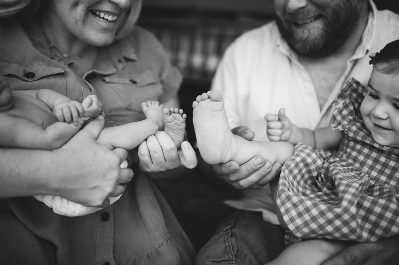 Fresh 48 Newborn Photography, a mother holds a new baby and dad sits close holding the older sister, everyone is happy
