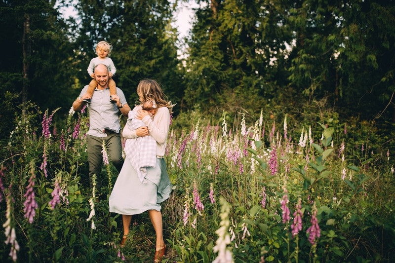 Family Photography - A young family walk through a meadow of lavender, they hold their young children in their arms