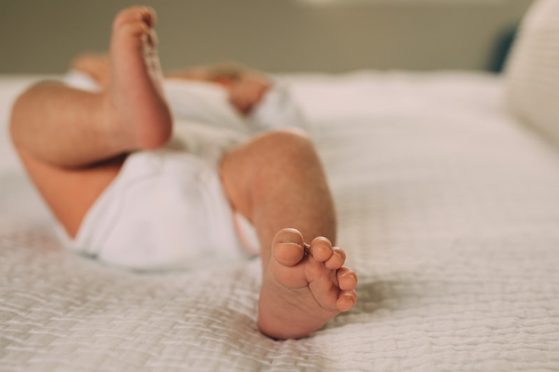 Fresh 48 Newborn Photography, a little baby lays on a bed comfortably
