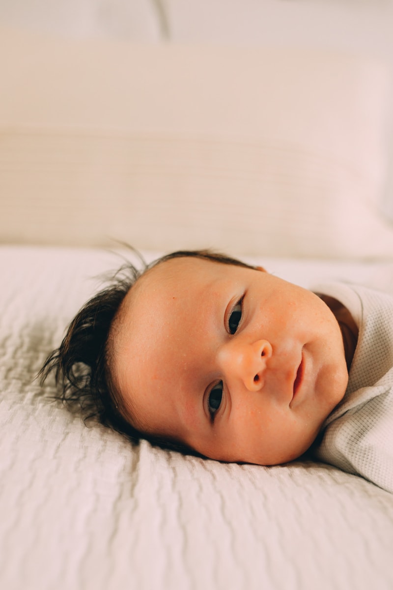 Fresh 48 Newborn Photography, a baby lays on linens at home looking very happy
