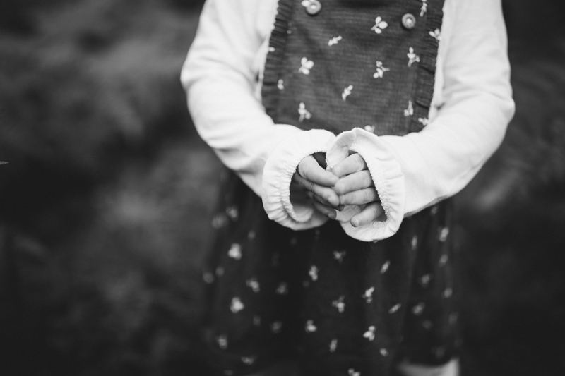 Milestone Photography, a baby girl stands in a grassy area, she holds her hands together,