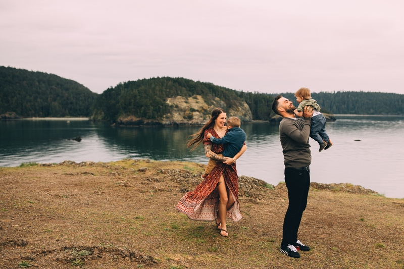 Family Photographer, young mom and dad carry their children around playfully near the lake