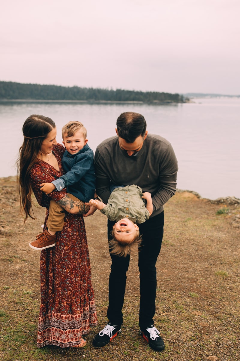 Family Photographer, a mother and father hold their two sons up playfully near the lake