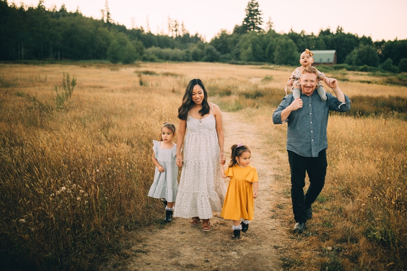 Family photographer, a young family walk through a dry meadow, mom, dad, and three little girls