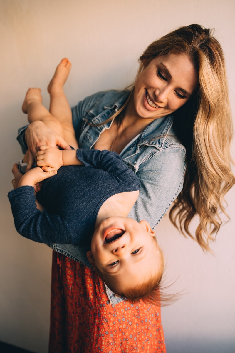 Motherhood Photography, a mother holds her big baby boy upside-down playfully, he laughs
