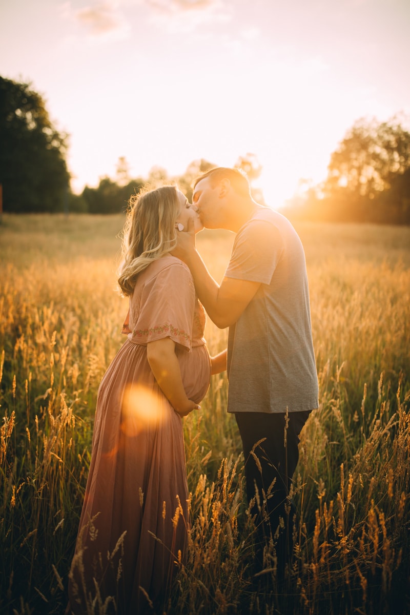 Family Photographer, a man and a woman kiss outside in a dry grassy meadow