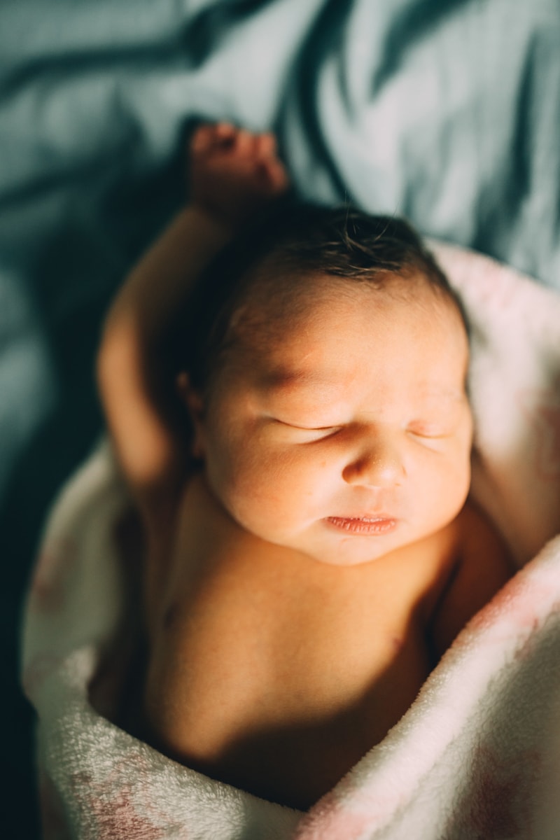 Fresh 48 Newborn Photography, a newborn baby lays wrapped in a hospital blanket comfortably sleeping