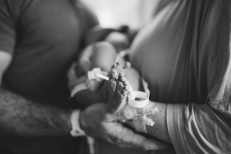 Fresh 48 Newborn Photography, a mother holds her new baby, dad draws in close to admire as well