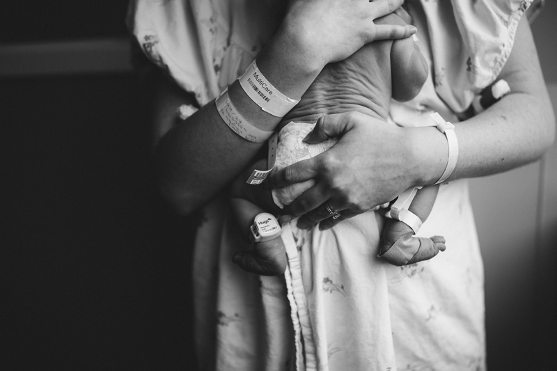 Fresh 48 Newborn Photography, a new mother holds onto baby while still in her hospital gown