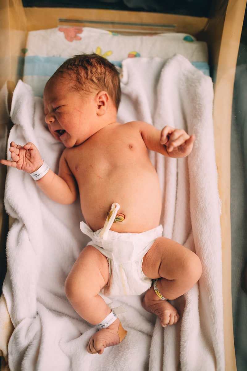 Fresh 48 Newborn Photography, a baby lays with diaper on and umbilical cord clipped in a hospital bassinet
