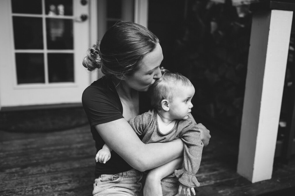 Mother kissing baby during in-home motherhood session