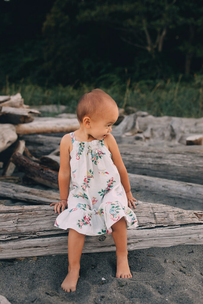 Little girl sitting on driftwood